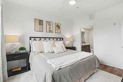A bedroom with a large bed and a nightstand with a lamp.