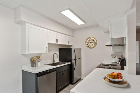 A kitchen with a black refrigerator and a clock on the wall.