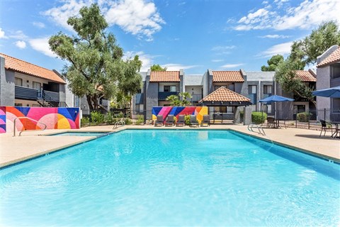 A swimming pool in front of a row of houses with a blue sky above.