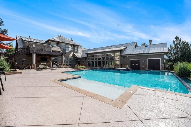 A large swimming pool is surrounded by a patio and a house.