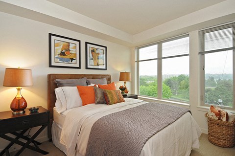 A bedroom with a large bed and two lamps.