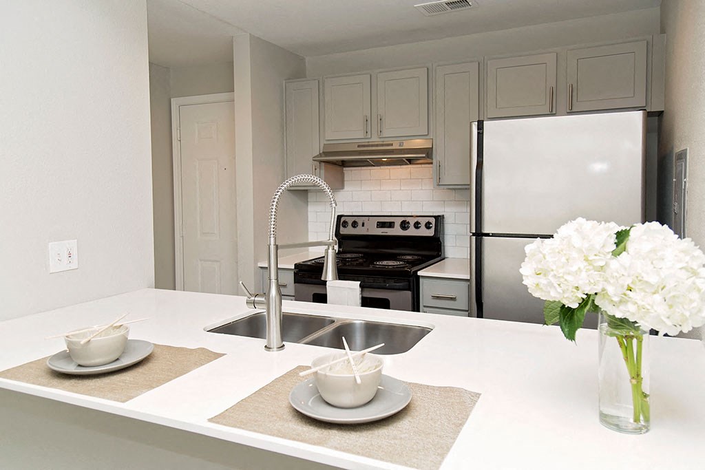 Model kitchen with place settings and floral arrangement on counter