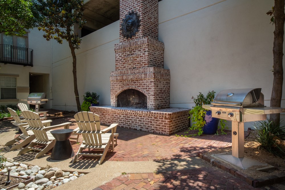 Outdoor chairs in front of BBQ and brick fireplace
