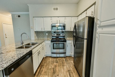 a kitchen with white cabinets and stainless steel appliances