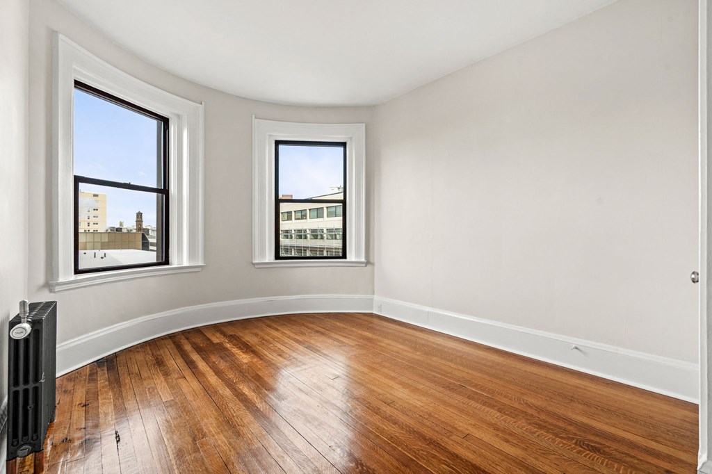 A room with wooden floors and two windows.