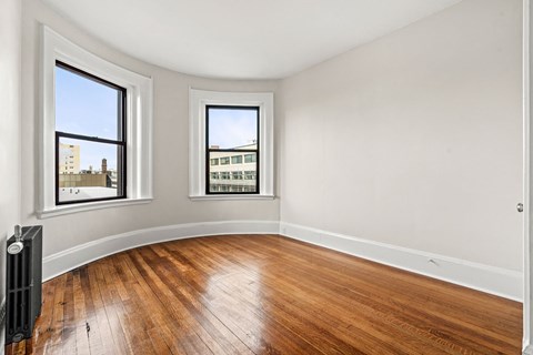 A room with wooden floors and two windows.