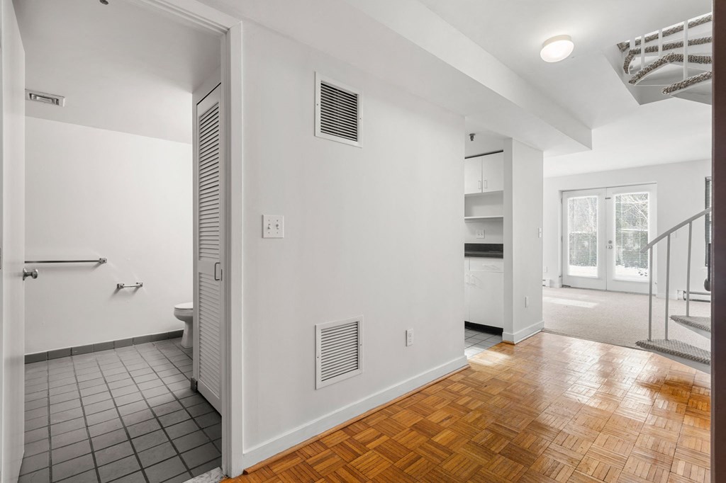 A white bathroom with a wooden floor and a white door.