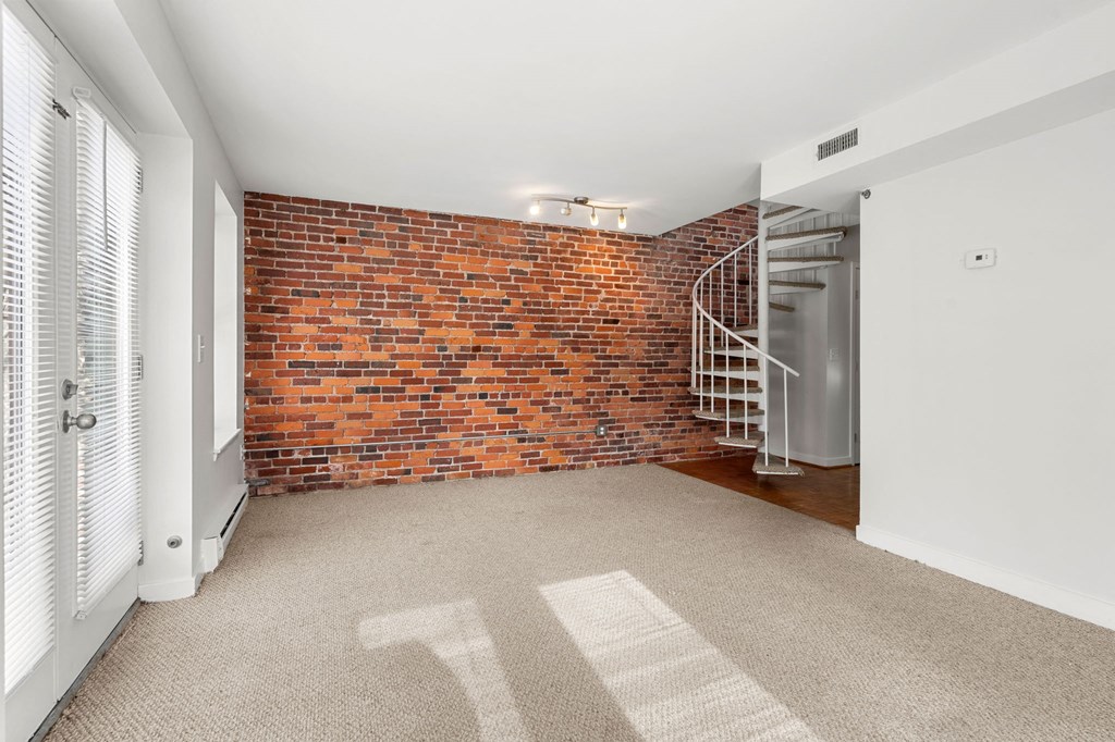 A room with a brick wall and a carpeted floor.