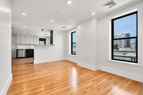 an empty living room with a large window and a kitchen