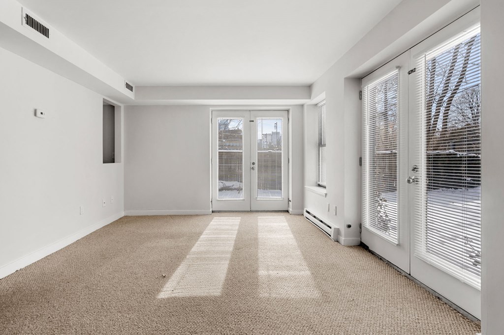 A room with a carpeted floor and a sliding glass door.