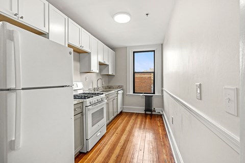 A kitchen with white appliances and wooden floors.