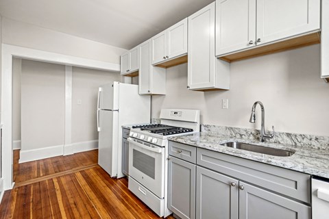 A kitchen with white appliances and wooden floors.