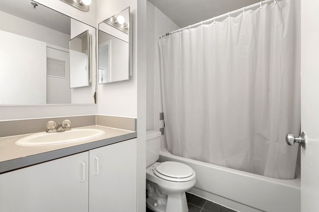 A white bathroom with a toilet, sink, and shower.