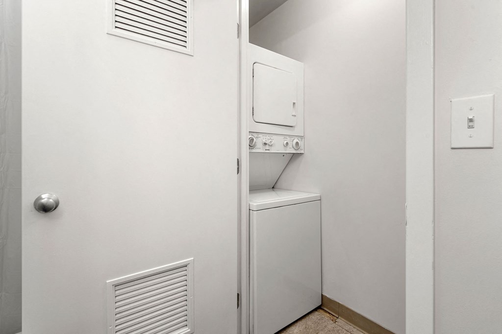 A white door is open to reveal a white cabinet with a microwave and oven.