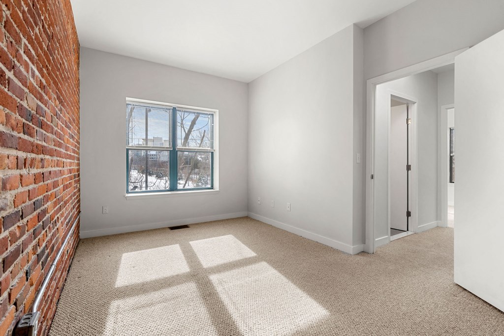 A room with a brick wall and a window.