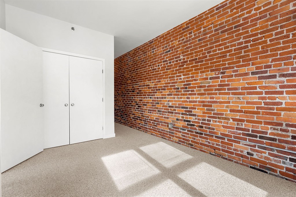 A room with a white door and a red brick wall.