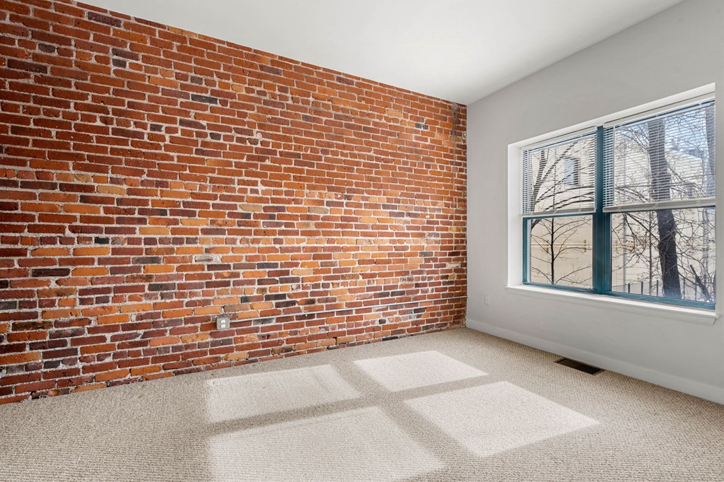 A room with a red brick wall and a large window.
