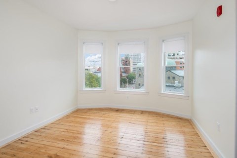 a living room with a wood floor and three windows