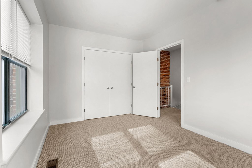 A room with a white door and a window with blinds.