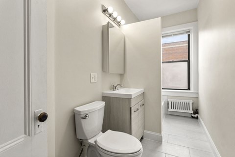 a bathroom with a toilet and a sink and a window