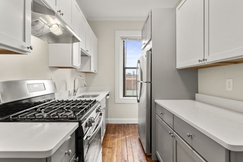 an empty kitchen with white cabinets and stainless steel appliances