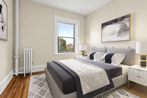 A bedroom with a large bed and a window overlooking a cityscape.