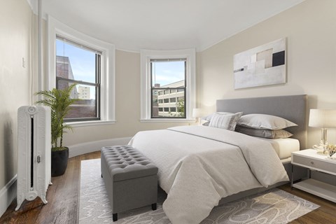 A bedroom with a large bed and a window overlooking a cityscape.