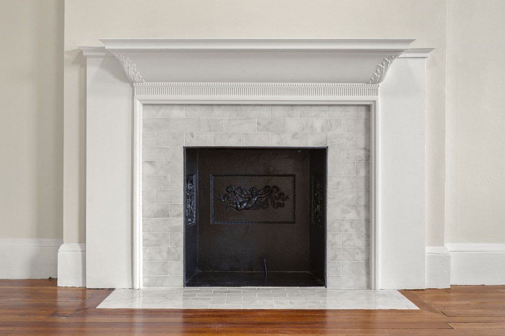 a fireplace in a living room with white walls and a wooden floor