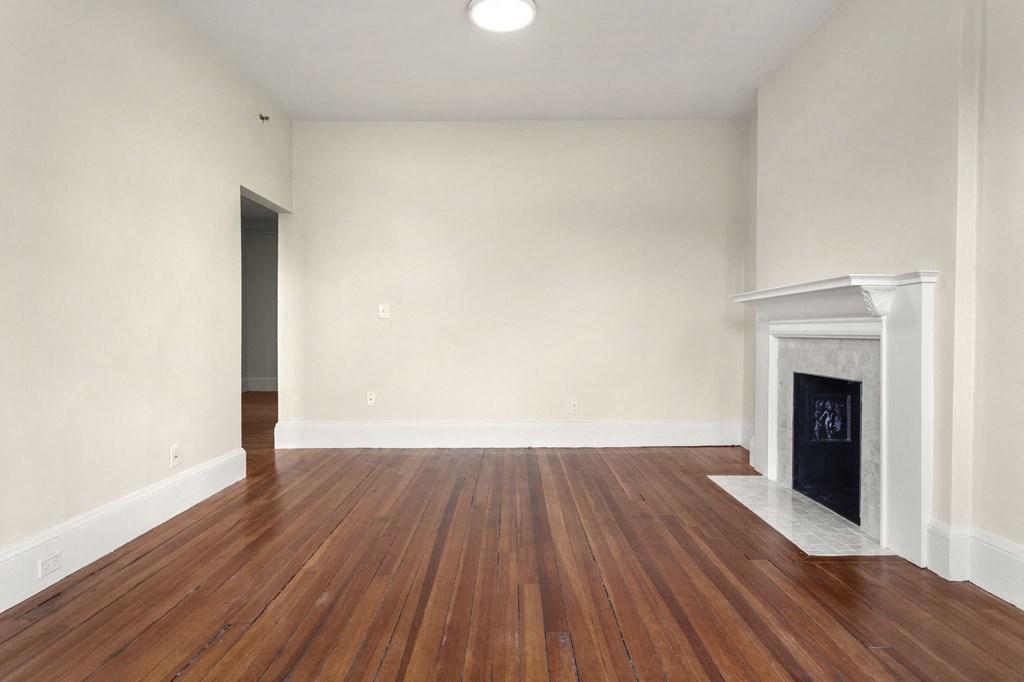 a living room with white walls and a fireplace and wooden floors