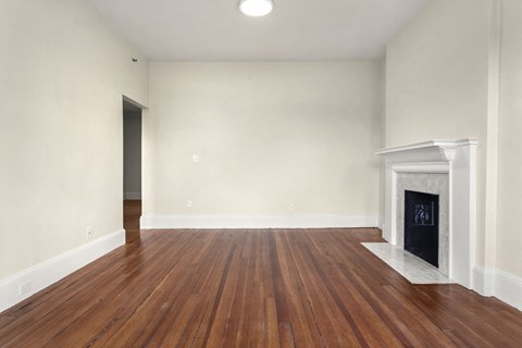 a living room with white walls and a fireplace and wooden floors