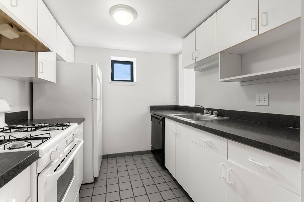 A kitchen with white cabinets and black countertops.