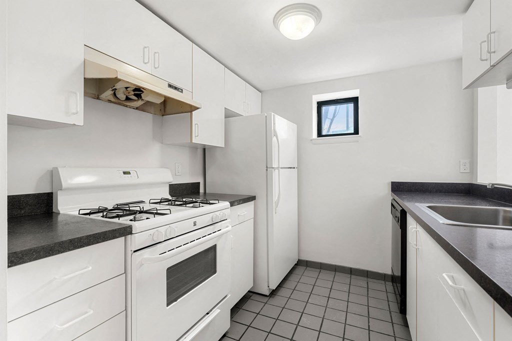 A kitchen with white cabinets and a black countertop.