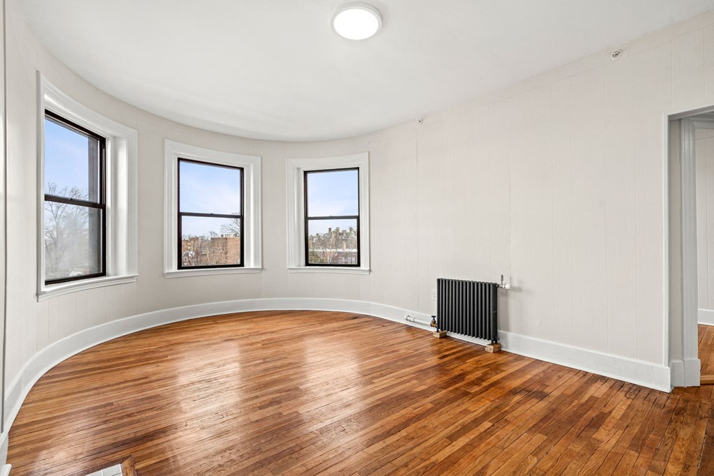 A room with a wood floor and three windows.