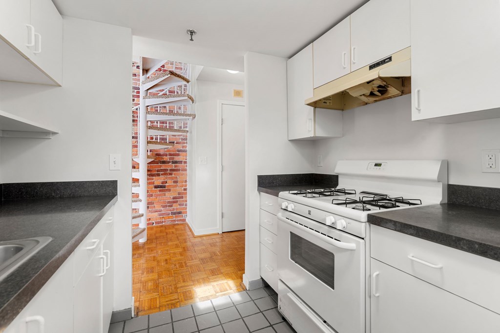 A kitchen with white cabinets and a brick wall in the background.