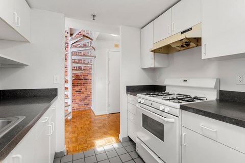 A kitchen with white cabinets and a brick wall in the background.