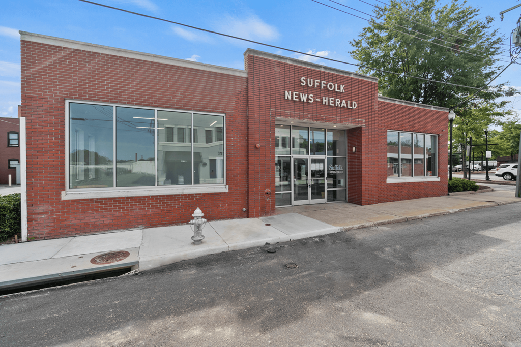 the front of a brick building with the words suffolk news herald
