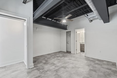the living room of a home with white walls and a gray floor and a door