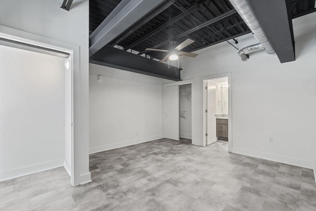 the living room of a home with white walls and a gray floor and a door