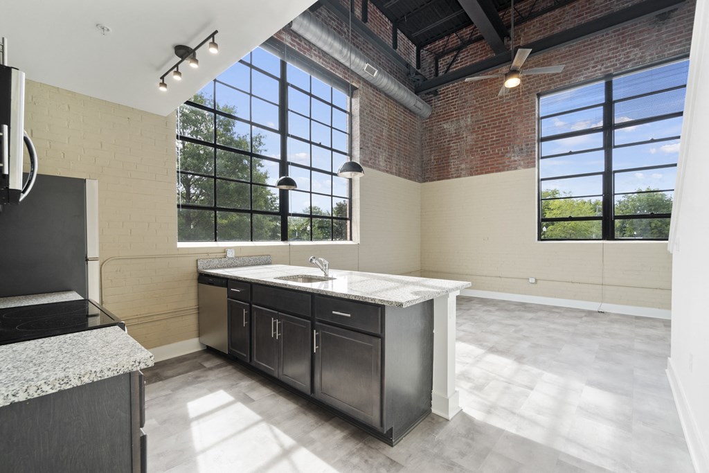 an empty kitchen with a large window and a sink and counter top