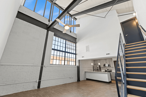 a living room with a staircase and a large window