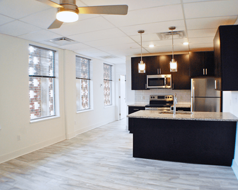 A kitchen with a black counter top and stainless steel appliances.