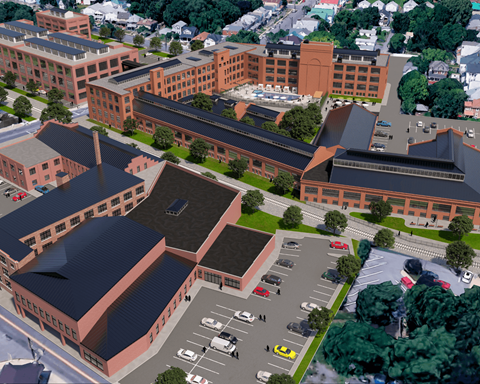 An aerial view of a large red brick building with a parking lot in front.