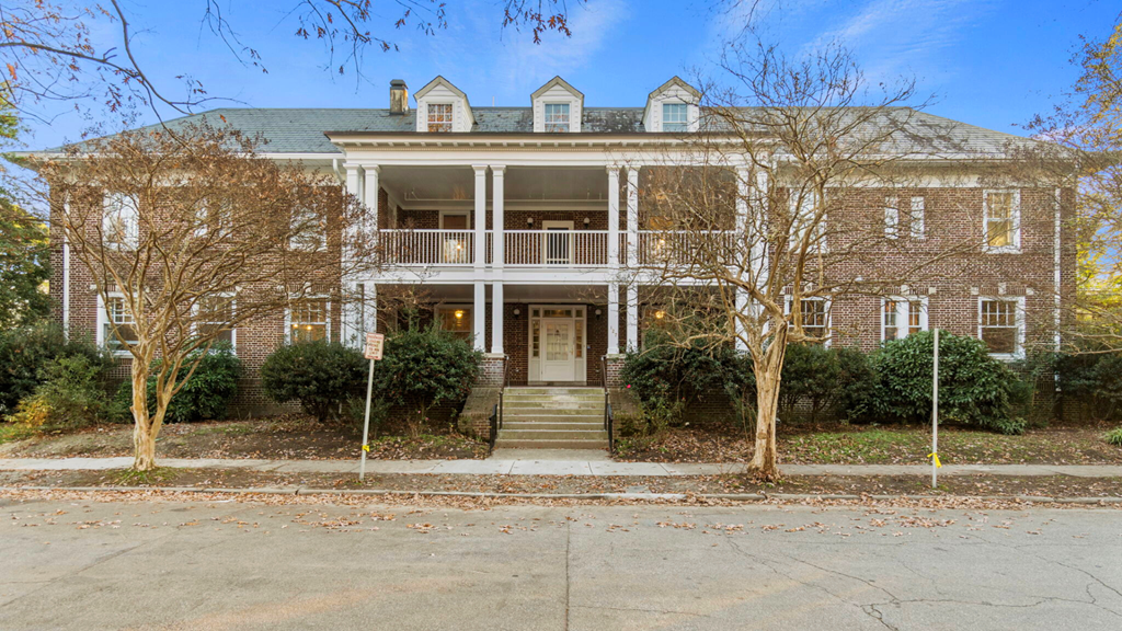 the front of a brick house with trees and stairs