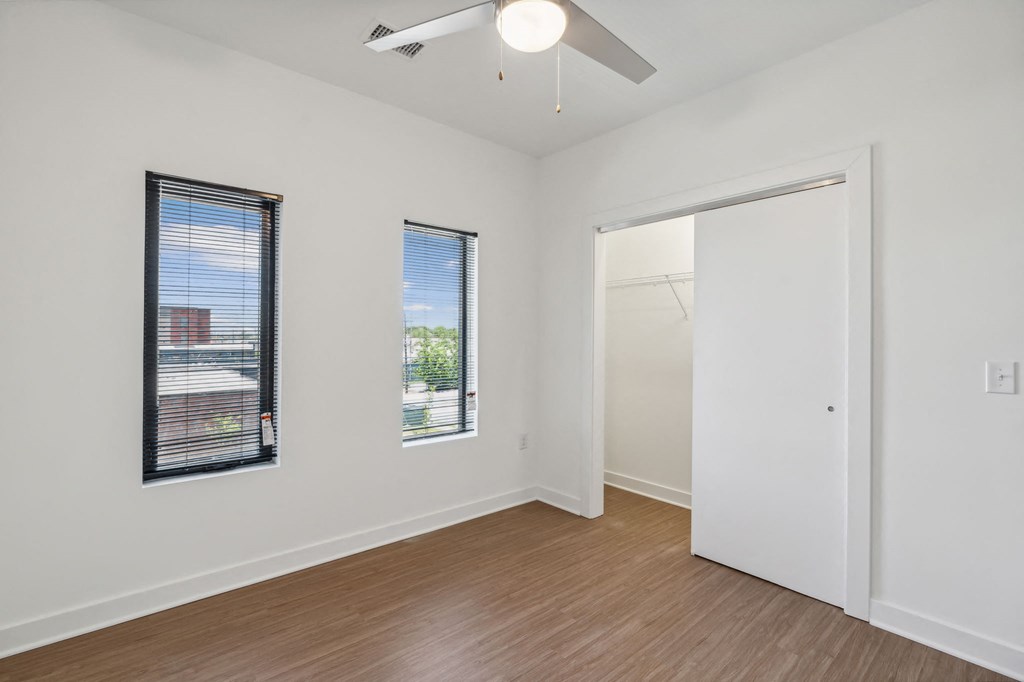 a living room with white walls and a window and a ceiling fan