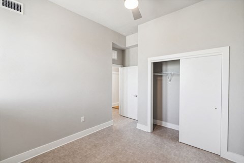 a bedroom with white walls and a closet with a mirrored closet door