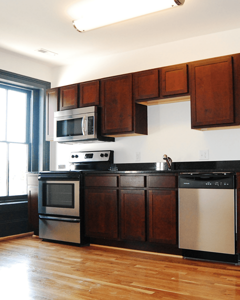 A kitchen with wooden cabinets and a black dishwasher.