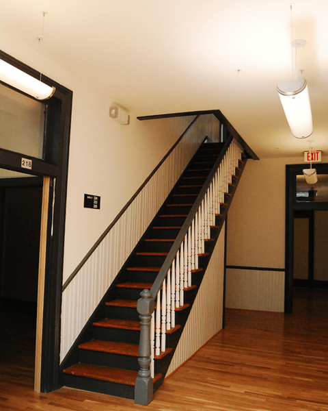 A staircase with a black railing and wooden steps.