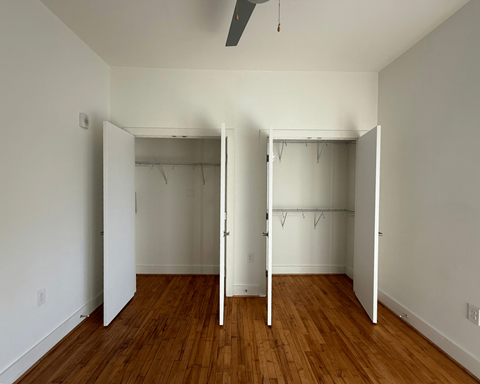 A room with two closets and a ceiling fan.