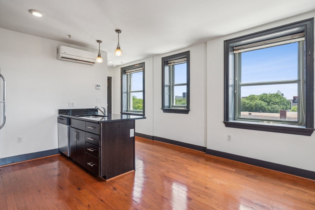 a living room with a hard wood floor and a kitchen with windows