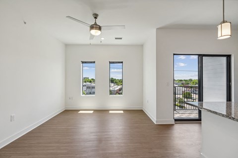 a living room with a hard wood floor and a door to a balcony